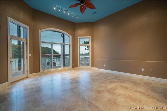 825 Grand View Dr, Porto Cima, MO 65079 - unfurnished room featuring rail lighting, ceiling fan, plenty of natural light, light tile patterned floors, and a towering ceiling