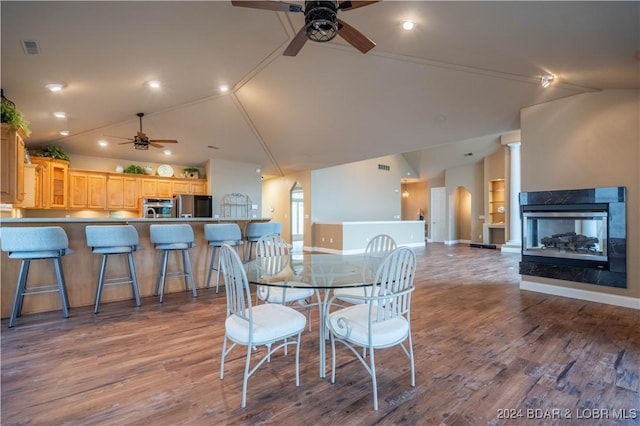 dining space with a multi sided fireplace, light wood-type flooring, vaulted ceiling, and ceiling fan