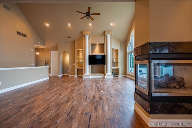 unfurnished living room with a multi sided fireplace, ceiling fan, hardwood / wood-style floors, and high vaulted ceiling