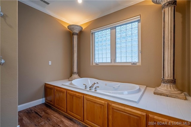 bathroom featuring hardwood / wood-style flooring, a tub, decorative columns, and crown molding