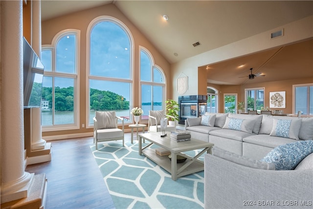 living room with hardwood / wood-style floors, a water view, high vaulted ceiling, and ceiling fan