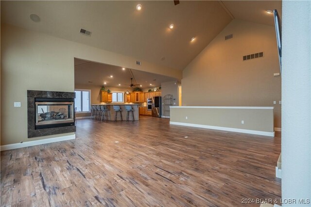 unfurnished living room with hardwood / wood-style flooring, a high end fireplace, and high vaulted ceiling