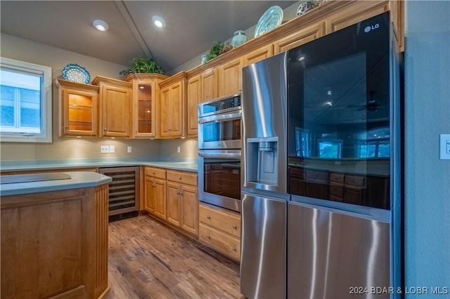 825 Grand View Dr, Porto Cima, MO 65079 - kitchen featuring appliances with stainless steel finishes, wine cooler, light countertops, wood finished floors, and glass insert cabinets