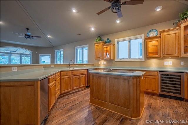 kitchen with dishwasher, sink, wine cooler, a kitchen island, and wood-type flooring