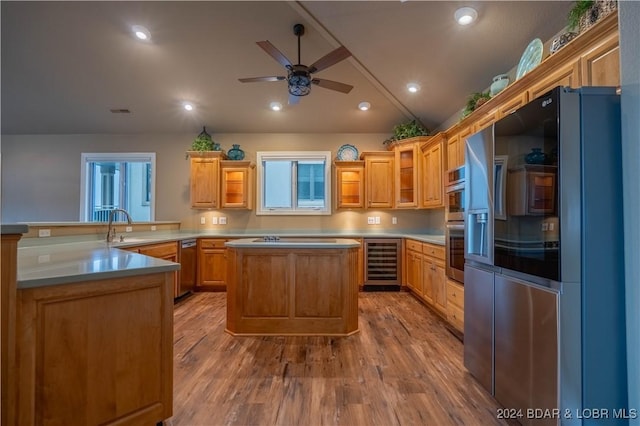 kitchen featuring a center island, wine cooler, light hardwood / wood-style flooring, kitchen peninsula, and appliances with stainless steel finishes