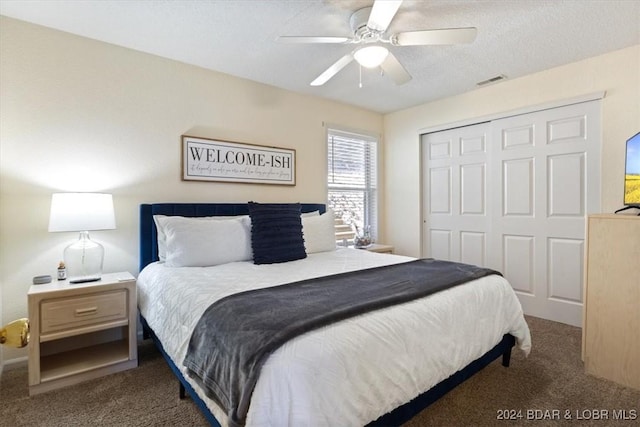 bedroom with ceiling fan, a closet, dark carpet, and a textured ceiling