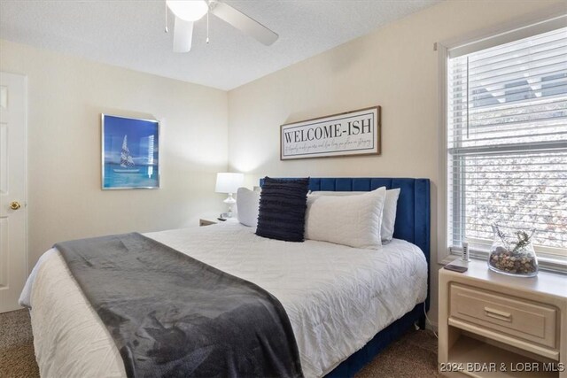 carpeted bedroom with ceiling fan and a textured ceiling