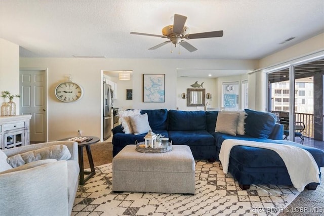 carpeted living room with ceiling fan and a textured ceiling