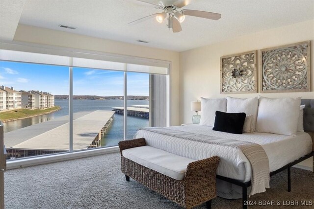 carpeted bedroom featuring ceiling fan, a water view, a textured ceiling, and access to outside