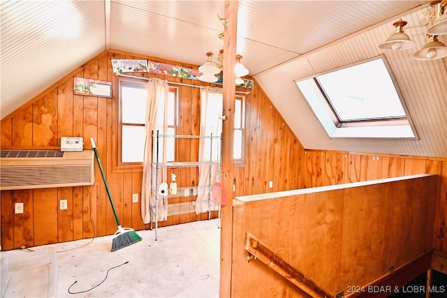 bonus room featuring vaulted ceiling with skylight, a healthy amount of sunlight, and wooden walls