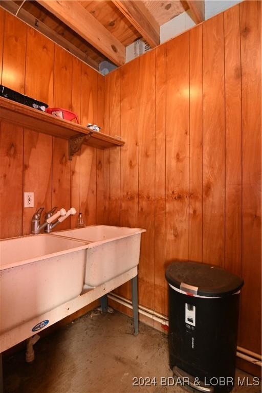 interior space with wood walls, sink, and concrete flooring