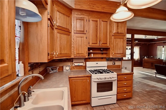 kitchen featuring pendant lighting, gas range gas stove, and sink