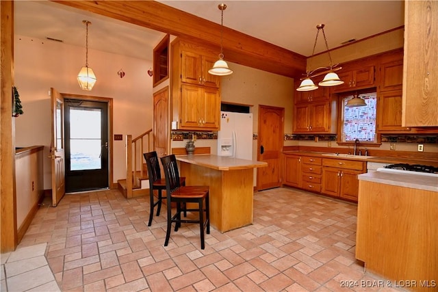 kitchen with white refrigerator with ice dispenser, decorative light fixtures, a breakfast bar area, and sink