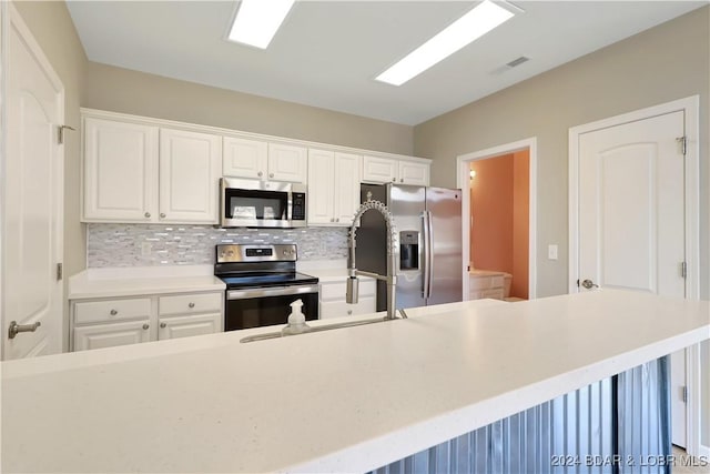 kitchen with decorative backsplash, white cabinetry, and stainless steel appliances