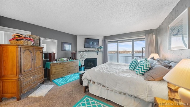 bedroom featuring access to exterior, a water view, light colored carpet, and a textured ceiling