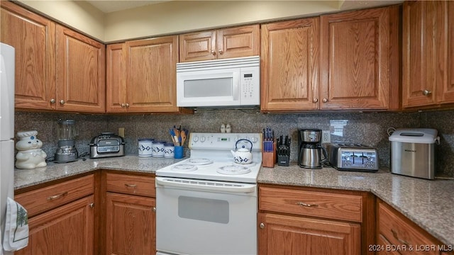 kitchen featuring backsplash, light stone counters, and white appliances