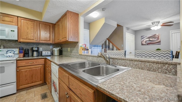 kitchen featuring white appliances, sink, ceiling fan, a textured ceiling, and tasteful backsplash