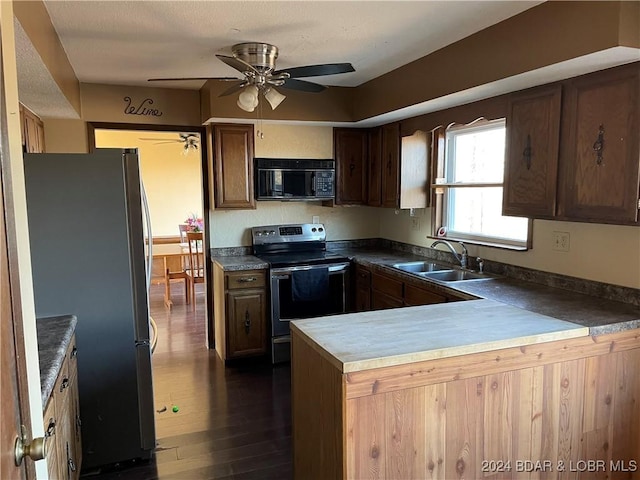 kitchen featuring ceiling fan, sink, dark wood-type flooring, kitchen peninsula, and appliances with stainless steel finishes