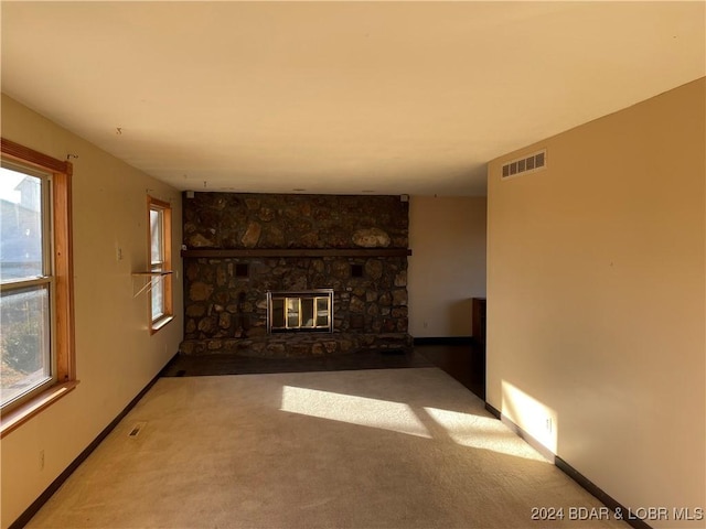 unfurnished living room with carpet flooring, a healthy amount of sunlight, and a fireplace