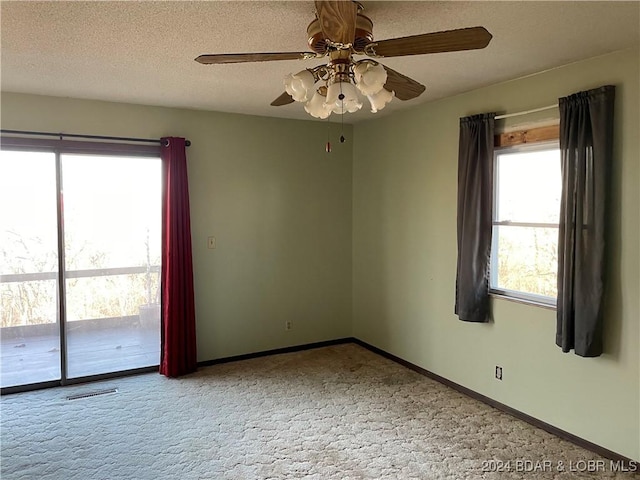 carpeted empty room with plenty of natural light, ceiling fan, and a textured ceiling