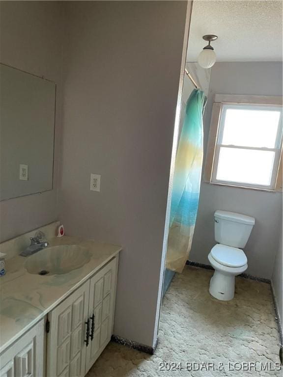 bathroom featuring a textured ceiling, vanity, and toilet