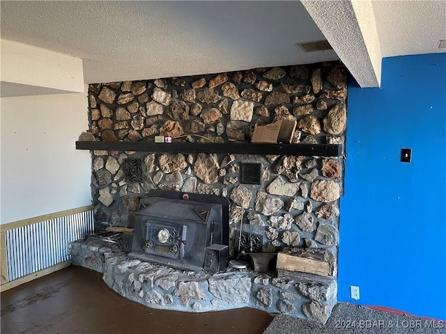 room details with a wood stove, concrete flooring, and a textured ceiling