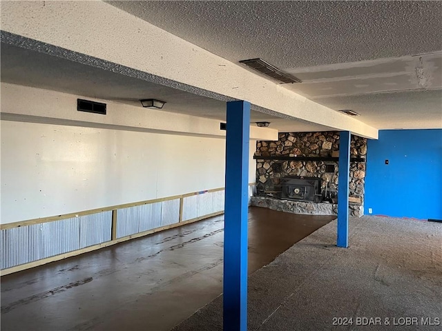 basement featuring a textured ceiling and a wood stove