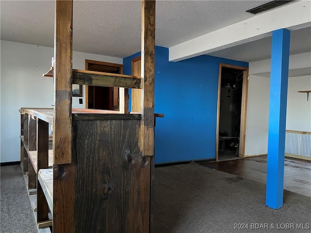 interior space with beamed ceiling, a textured ceiling, and dark colored carpet