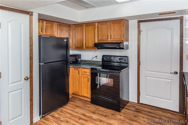 kitchen featuring tasteful backsplash, wood-type flooring, and black appliances