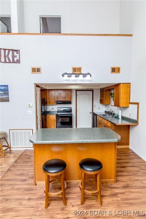 kitchen with light hardwood / wood-style flooring, a breakfast bar, range, and kitchen peninsula