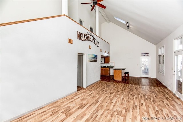 unfurnished living room featuring ceiling fan, high vaulted ceiling, and light hardwood / wood-style flooring