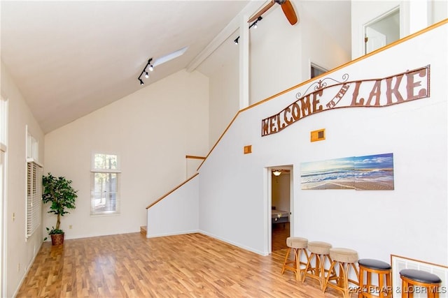 interior space with beamed ceiling, high vaulted ceiling, and hardwood / wood-style floors