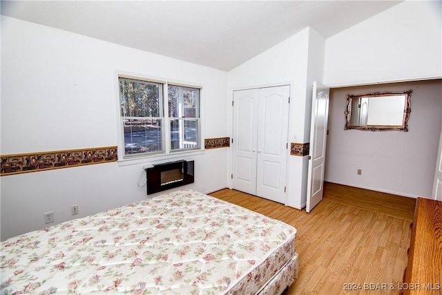 unfurnished bedroom featuring vaulted ceiling, light hardwood / wood-style floors, and a closet