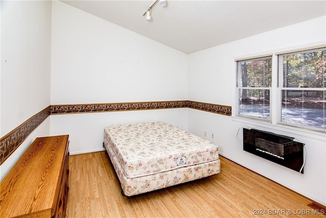 bedroom with hardwood / wood-style flooring and track lighting