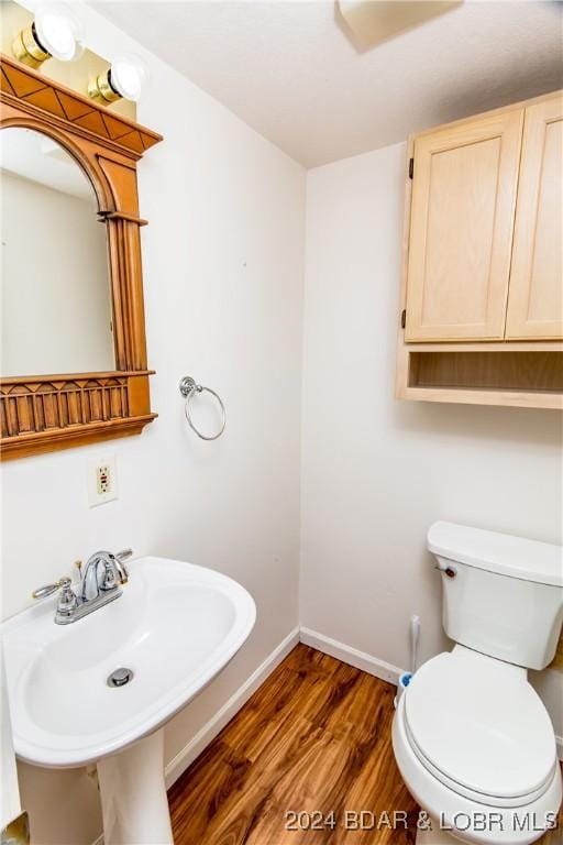 bathroom with wood-type flooring, toilet, and sink