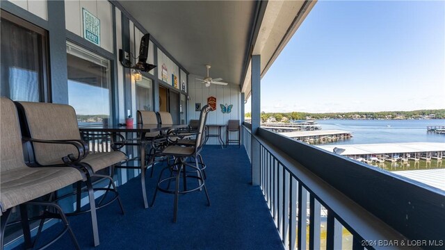 balcony featuring a ceiling fan and a water view