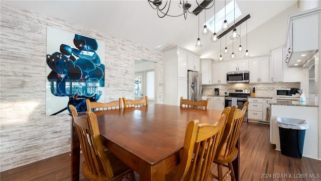 dining space with dark hardwood / wood-style flooring, lofted ceiling with skylight, and an inviting chandelier