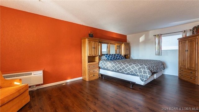 bedroom with a textured ceiling, an AC wall unit, and dark wood-type flooring