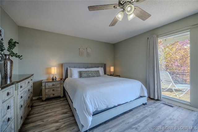 bedroom featuring ceiling fan, wood-type flooring, a textured ceiling, and multiple windows