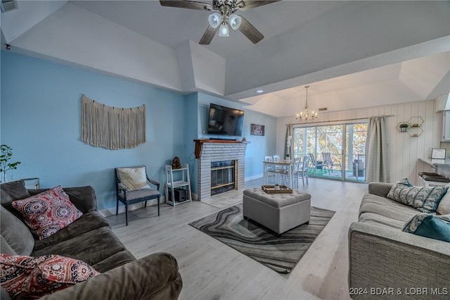 living room featuring a brick fireplace, ceiling fan with notable chandelier, light hardwood / wood-style flooring, and vaulted ceiling