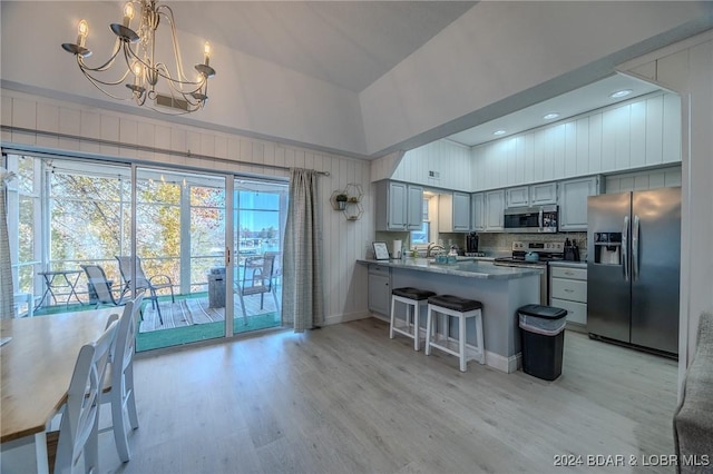 kitchen with gray cabinetry, hanging light fixtures, kitchen peninsula, light hardwood / wood-style floors, and appliances with stainless steel finishes