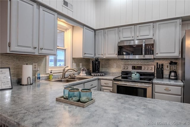 kitchen with tasteful backsplash, gray cabinetry, sink, and appliances with stainless steel finishes