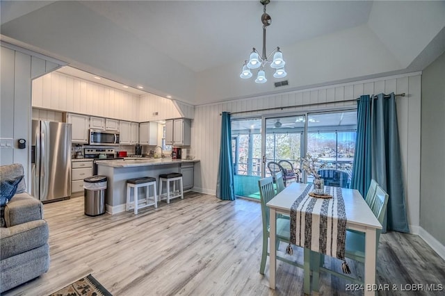 dining space featuring a raised ceiling, light hardwood / wood-style flooring, a notable chandelier, and sink