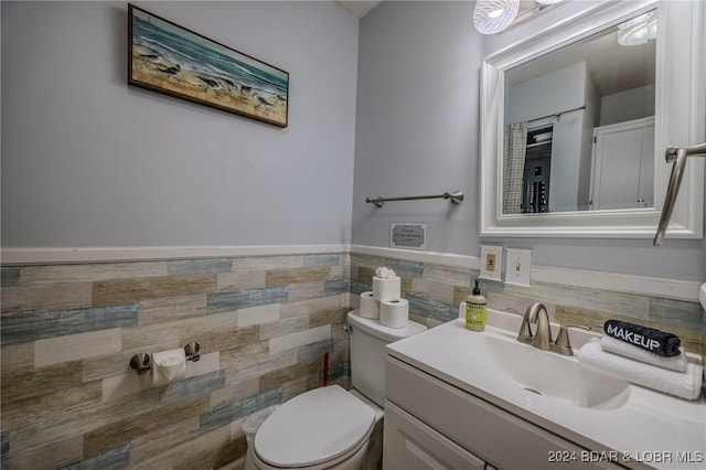 bathroom featuring vanity, tile walls, and toilet