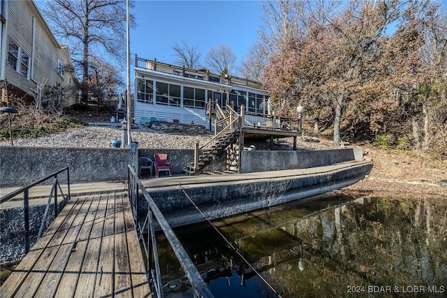 back of property with a sunroom and a water view