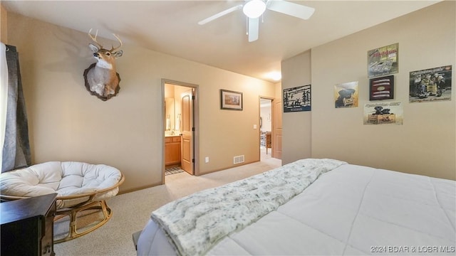 carpeted bedroom with ensuite bathroom and ceiling fan