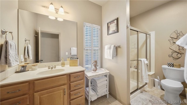 bathroom with tile patterned floors, vanity, a shower with shower door, and toilet