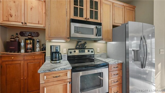 kitchen with light stone countertops and appliances with stainless steel finishes