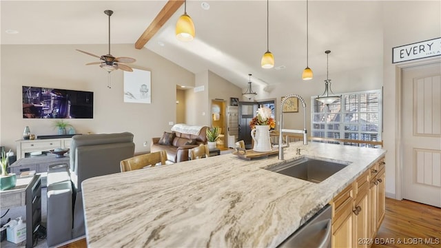 kitchen featuring light stone counters, ceiling fan, sink, decorative light fixtures, and vaulted ceiling with beams