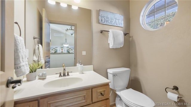 bathroom featuring vanity, toilet, and vaulted ceiling